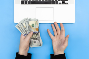 Person holding cash in front of a computer